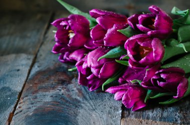 Koyu ahşap bir masa üzerinde mor laleler