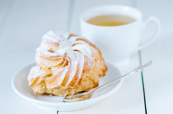 Choux pastry whith a cup of tea on the white wooden table — Stock Photo, Image