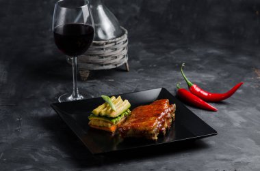 Tabakta ızgara pirzola, sebze ve siyah arka planda şarap. Lezzetli bbq eti.
