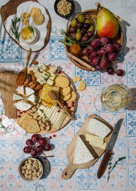 Masada çeşit çeşit aperatiflerle peynir tabağı. Taze Brie peyniri ve camembert peyniri kraker, armut, üzüm, zeytin, biberiye, portakal reçeli, fındık, bal peteği ve şarap. Üst görünüm