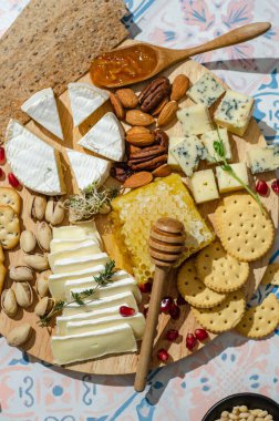 Masada çeşit çeşit aperatiflerle peynir tabağı. Taze brie peyniri ve peynirli camembert peyniri kraker, biberiye, portakal reçeli, portakal reçeli, fındık, bal peteği ve şarap..