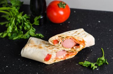 Sosis ve sebzeli sulu shawarma. Konsept: fast food. Domatesli, baharatlı ve otlu siyah arkaplan