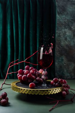 Altın tepside kırmızı üzümlü kırmızı şarap. Şarap sıçratıyorum. Fotoğraf modern tarzda..