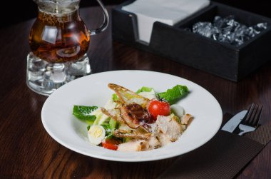 Kahverengi ahşap bir masada tavuk sezar salata peyniri ve pastırma. Yemekler restoranda.