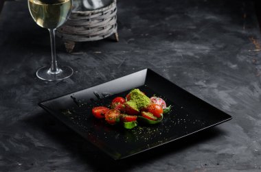 Taze domates salatası ve fesleğen. Lokantada yemek, karanlık bir masada.