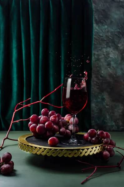Altın tepside kırmızı üzümlü kırmızı şarap. Şarap sıçratıyorum. Fotoğraf modern tarzda..