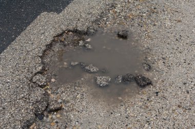 Asfalt yol ile su ve asfalt taşlarla dolu çukur