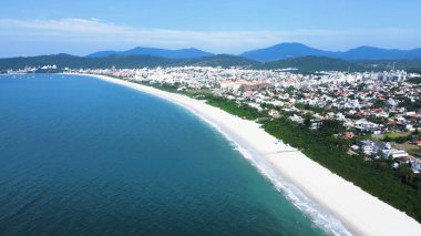 Florianpolis, Santa Catarina 'daki Jurere Internacional plajı, lüks evler, sahil kulüpleri, güneşli bir günde turkuaz mavisi deniz üzerinde lüks bir turistik sahilde lüks okyanus manzaralı evler..