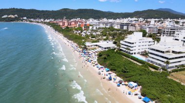 Florianpolis, Santa Catarina 'daki Jurere Internacional plajı, lüks evler, sahil kulüpleri, güneşli bir günde turkuaz mavisi deniz üzerinde lüks bir turistik sahilde lüks okyanus manzaralı evler..