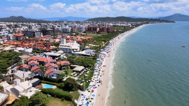 Florianopolis, Santa Catarina 'daki Jurere Uluslararası plajının havadan görünüşü, lüks evler, sahil kulüpleri, güneşli bir günde turkuaz mavi denizde lüks bir turistik bölgede lüks okyanus kıyısında konutlar..