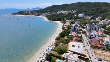 Florianopolis, Santa Catarina 'daki Jurere Uluslararası Sahili' nin panoramik hava manzarası. Lüks evler ve sahil kulüpleri deniz kenarında, tekneler, yatlar ve turkuvaz mavisi okyanusta yelkenliler..