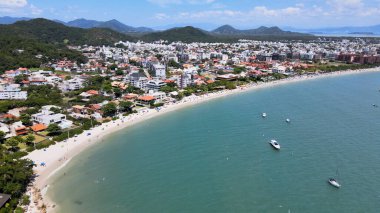 Florianopolis, Santa Catarina 'daki Jurere Uluslararası Sahili' nin panoramik hava manzarası. Lüks evler ve sahil kulüpleri deniz kenarında, tekneler, yatlar ve turkuvaz mavisi okyanusta yelkenliler..