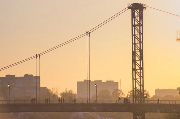 Silhueta de pessoas que viajam através da ponte — Fotografia de Stock