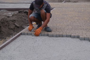Terasa, yola ya da kaldırıma kaldırım taşları döşeyip döşeyen inşaat işçisi. Kaldırımlar için taş kullanan işçiler