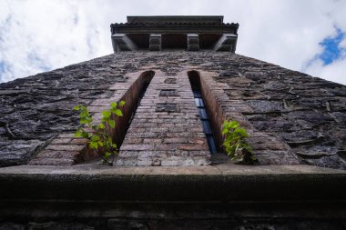Bulutlu arka planda duvarlardan büyüyen huş ağaçlı dış kale.