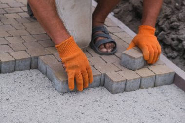 Terasa, yola ya da kaldırıma kaldırım taşları döşeyip döşeyen inşaat işçisi. Kaldırımlar için taş kullanan işçiler