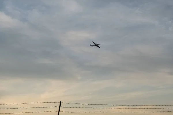 Ett Jetinflygningslandning Med Taggtrådsstängsel Förgrunden Kvällen Himmel Bakgrund — Stockfoto