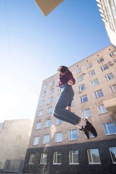 魅力的な若いブルネットの女性はカジュアルなストリートウェアを着て 建物の近くにジャンプします — ストック写真