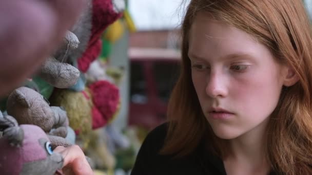 Girl looks at old dirty stuffed dolls on the street — Stock Video