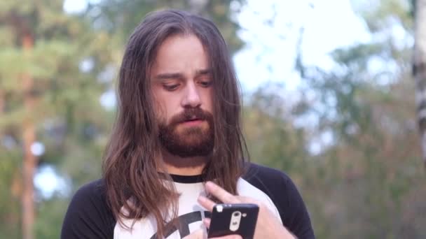 Bearded man uses mobile phone in the park — Stock Video