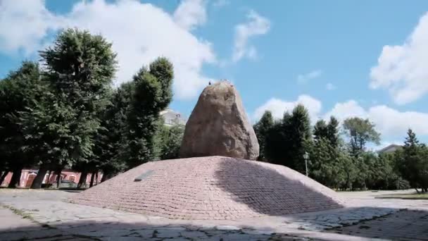 Een grote ongewone steen op een met mos bedekte rotsachtige vlakte tegen een bewolkte lucht — Stockvideo