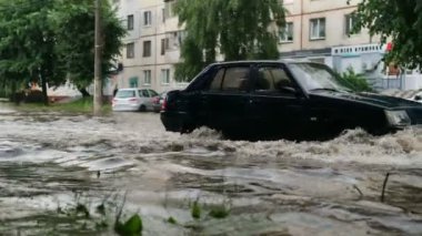 Zhytomyr, Ukrayna - 27 Haziran 2021: Şiddetli yağmurda sel altındaki caddede araba trafiği.