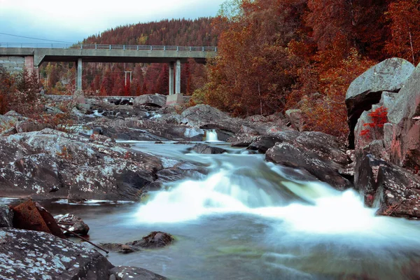 concrete bridge nature autumn landscape. Gray concrete bridge across a clean blue river in Norway