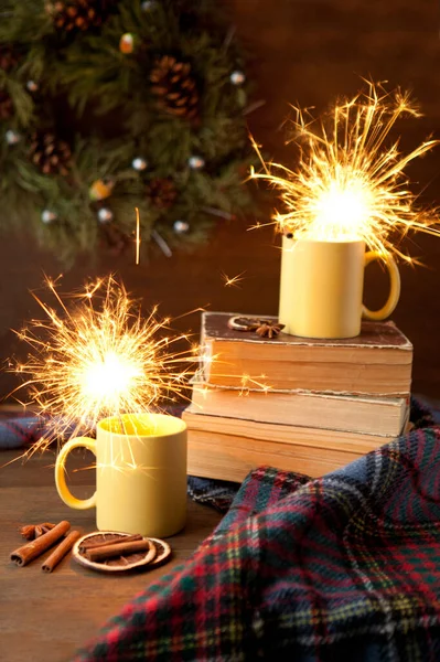 Tea cups with sparkle and christmas background, ceramic cup with bright light inside, books and blanket with scrolls and cinnamon — Stock Photo, Image