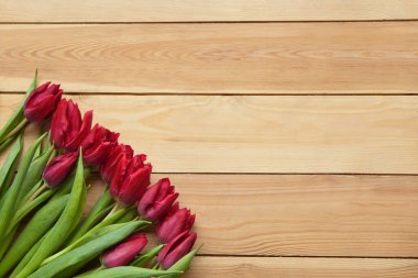 Tahta masadaki kırmızı bahar laleleri. Çiçek açan kırmızı yapraklar. Baharda güzel laleler. Ahşap arka planda yeşil yapraklı lale çiçeği