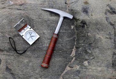 Jeologlar taşlara çekiçle pusula kurarlar. Jeoloji bilimi kavramı. Jeologlar çekiç ve aletler bir taşın üzerine serilmiştir.