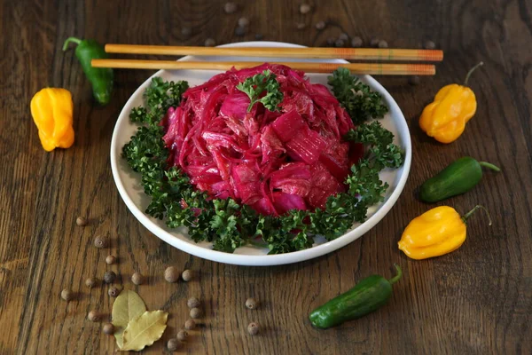 Корейский салат из капусты со свеклой на тарелке с перцем. Вкусная азиатская кухня — стоковое фото