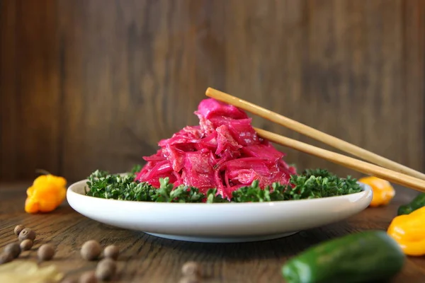 Корейский салат из капусты со свеклой на тарелке с перцем. Вкусная азиатская кухня — стоковое фото