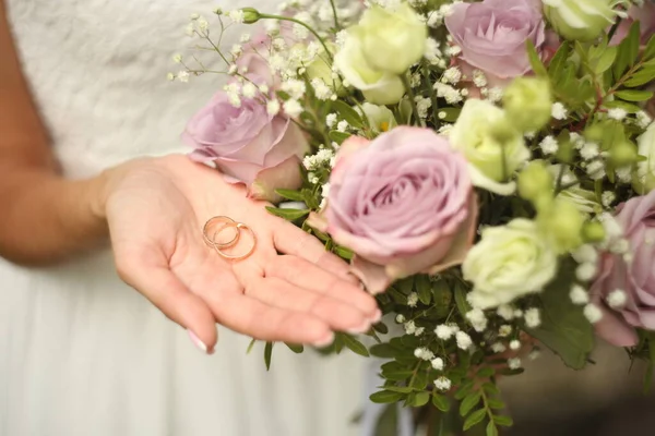 Alliances sur la main de la mariée avec des roses violettes - mariée tenant une bague — Photo