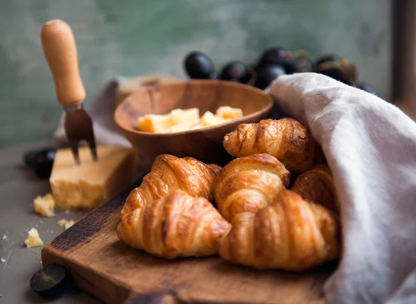 Croissants whit delicious cheese and grapes for tasty breakfast. Original tasty French croissants with cheese and on the wooden table.