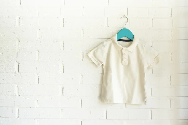 White polo shirt hanging on a blue hanger