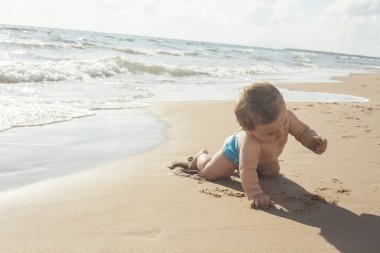 Deniz kıyısı kuma dokunmadan erkek bebek.