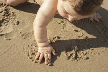 Deniz kıyısı kuma dokunmadan erkek bebek.