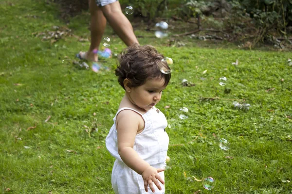 Девушка играет с мыльными пузырями в саду — стоковое фото