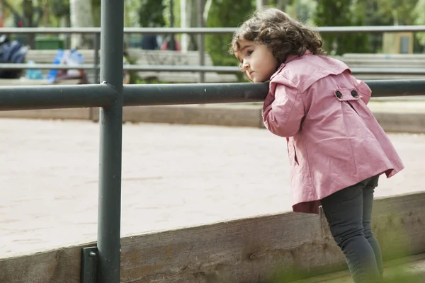 Menina olhando para o parque infantil — Fotografia de Stock