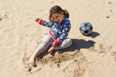 Paskalya rüzgarlı bir günde plaj kum ile oynayan kız