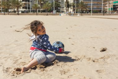 Paskalya rüzgarlı bir günde plaj kum ile oynayan kız