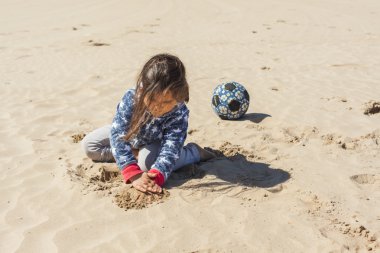 Paskalya rüzgarlı bir günde plaj kum ile oynayan kız
