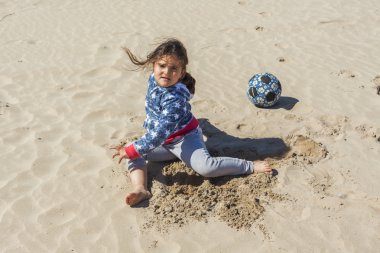 Paskalya rüzgarlı bir günde plaj kum ile oynayan kız