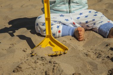 Bebek çocuk sahilde kum oyuncakları ile oynarken kapatmak.