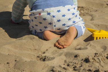 Sahilde kum oyuncakları ile oynarken erkek bebek kapatın. Arkadan görünüş