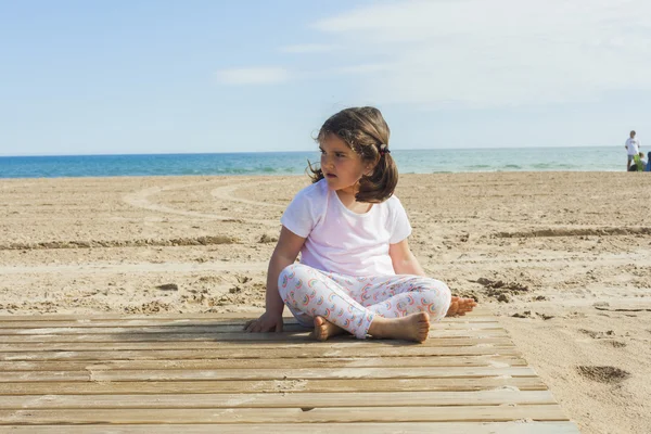 Ragazza che gioca con la sabbia in spiaggia in una giornata di sole in primavera — Foto Stock