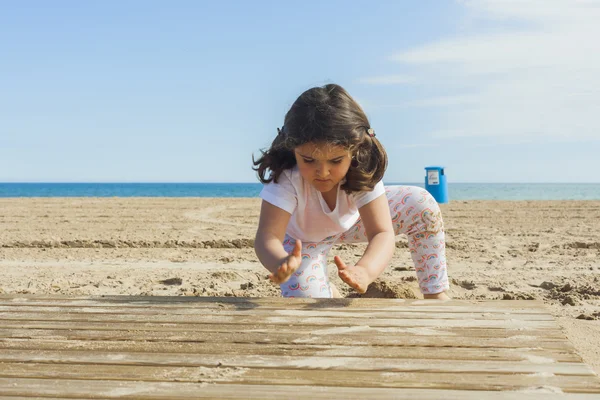 Ragazza che gioca con la sabbia in spiaggia in una giornata di sole in primavera — Foto Stock