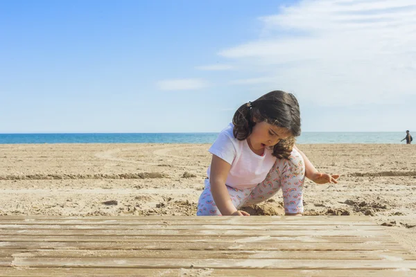 Ragazza che gioca con la sabbia in spiaggia in una giornata di sole in primavera — Foto Stock