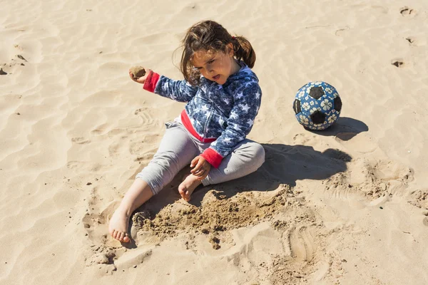 Paskalya rüzgarlı bir günde plaj kum ile oynayan kız