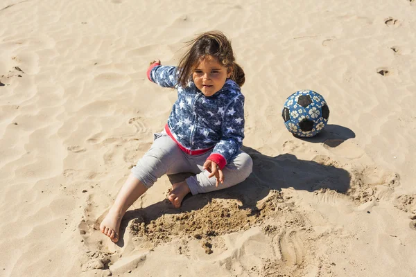 Ragazza che gioca con la sabbia in spiaggia in una giornata ventosa a Pasqua — Foto Stock